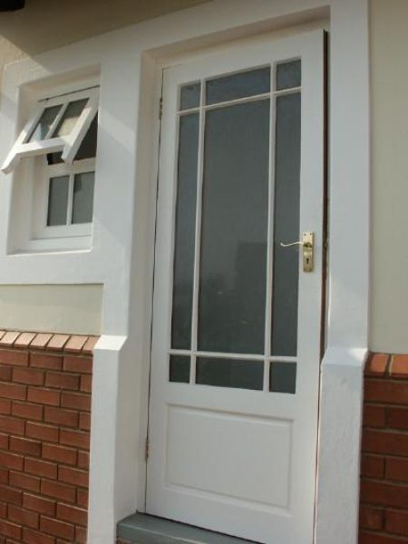 Outside view of the Meranti 'Happy' 813 mm x 2032 mm Glass Top Exterior Door shown installed on a building